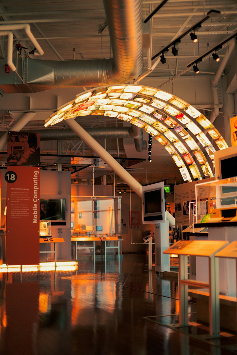 Moderná múzejná expozícia so žiariacou bránou a odrazmi.